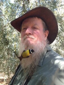 Man in an Akubra hat with a small yellow and black bird clinging to his beard