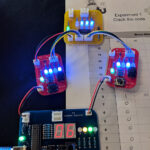 Coding experiment using wires and four circuit boards with buttons and lights