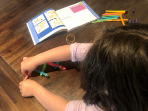A young child sitting at a table and using icy pole sticks to test out activities from More Hands-On Science.