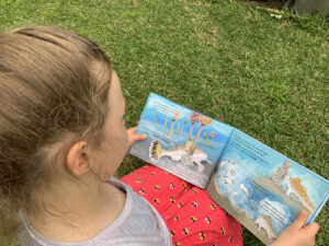 Over the shoulder view of a young girl reading Hold On picture book