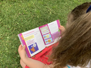 A photo of a young girl taken from over her shoulder reading More Hands-On Science