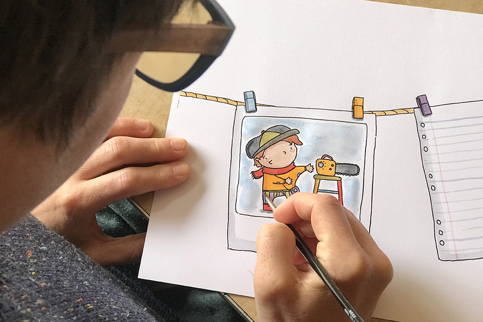 A close-up photo of Brenna Quinlan using watercolour paints to colour in an illustration from Bee Detectives.