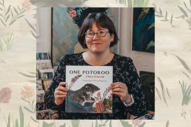 Illustrator Alicia Rogerson smiling at the camera as she sits in her studio, surrounded by her art, holding a copy of One Potoroo. The photo is overlaid on a background illustration of Australian native flowers and plants.