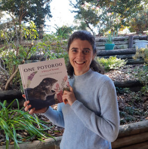 Author Penny Jaye smiling and holding a copy of her book One Potoroo