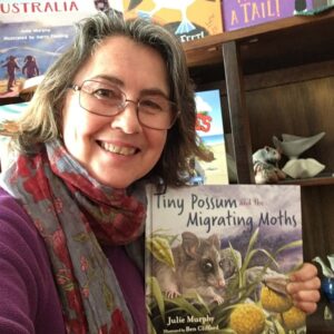 Julie Murphy smiling and holding a copy of Tiny Possum and the Migrating Moths.