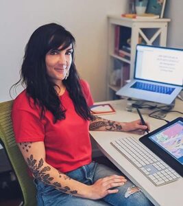 Rachel Tribout sits at her desk, working on illustrations