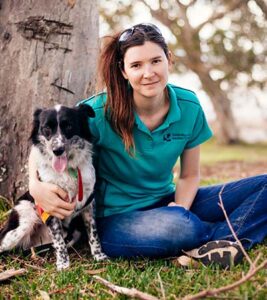 Romane Cristescu sits under a tree with her arm around a dog