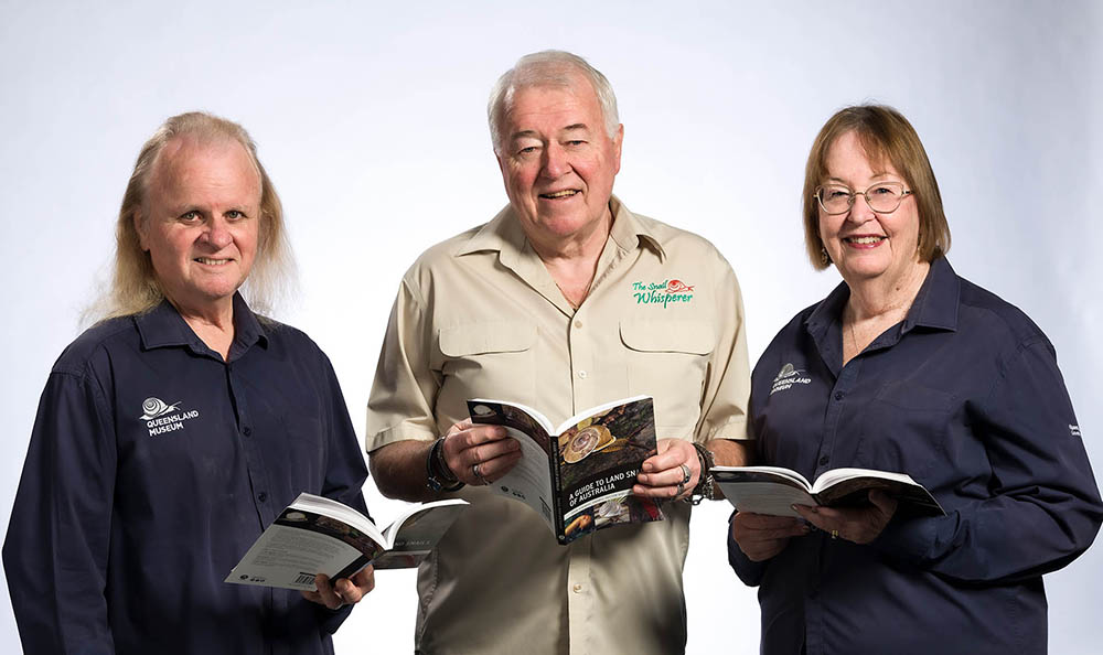 Authors, Darryl Potter, John Stanisic and Lorelle Stanisic, smiling and all holding a copy of A Guide to Land Snails of Australia.