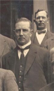 A sepia-toned photograph of two men in suits and ties.