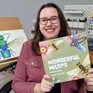 Suzanne Houghton smiling and holding the picture book 'Wonderful Wasps'.