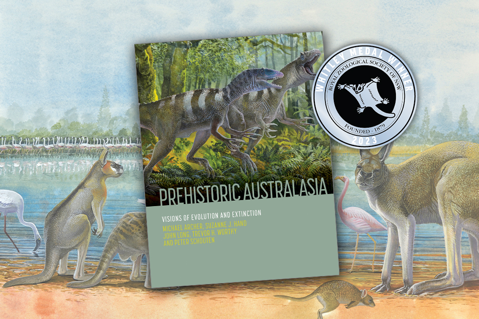 The book 'Prehistoric Australasia' alongside the 2023 Whitley Medal Winner sticker. Behind the book cover is a painted scene of prehistoric animals gathered at a lake.