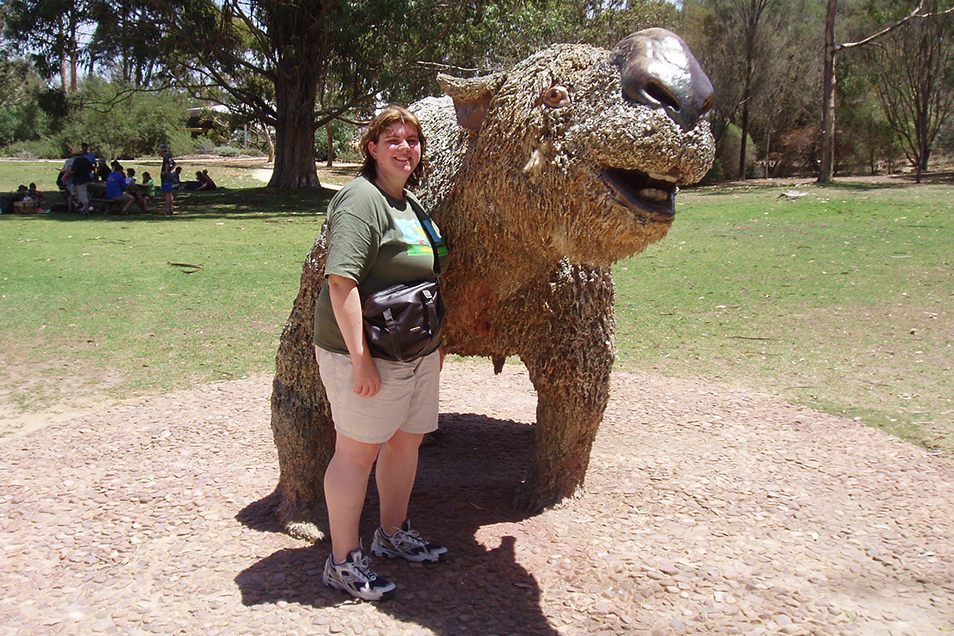 Bronwyn Saunders stands in front of a life-size diprotodon statue, smiling.